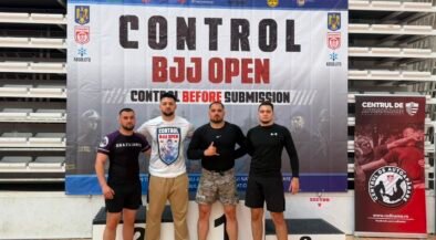 Four men stand on a winners podium in front of a banner that reads 'CONTROL BJJ OPEN', posing for a photo at a martial arts event.