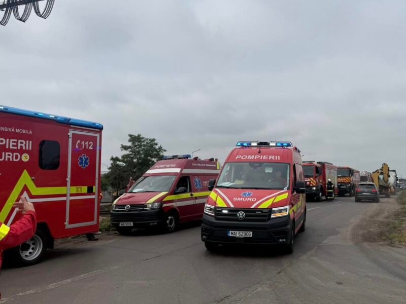 Convoy of red emergency vehicles, including SMURD ambulances, parked on a road under a cloudy sky